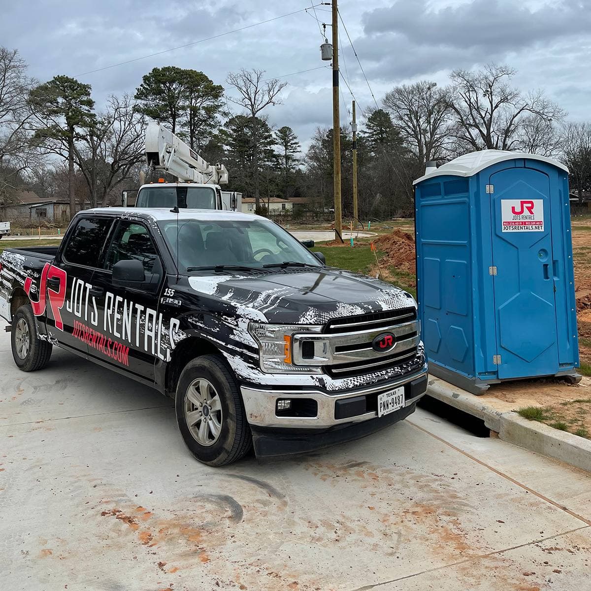 A JOTS Rentals service truck alongside a portable restroom